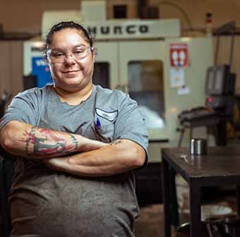 Student standing in manufacturing facility