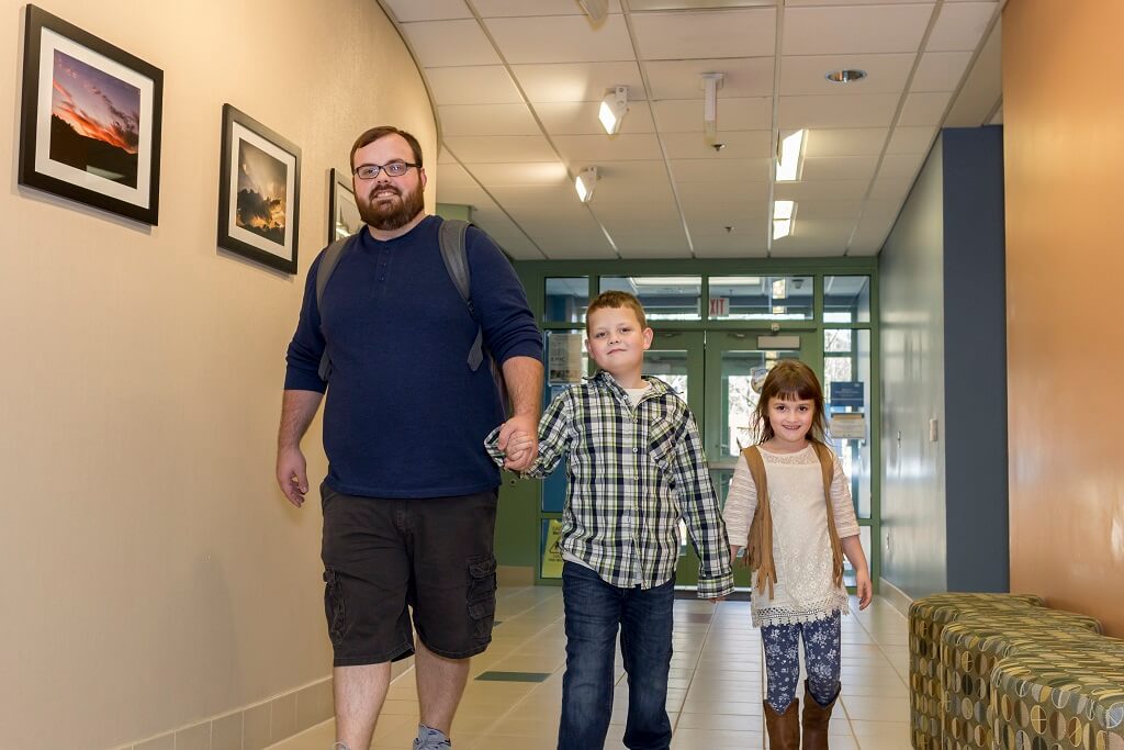 SKCTC father walking through a building on campus with his two children